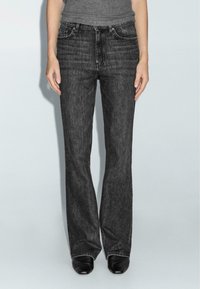 Jeans in denim nero con taglio dritto, caratterizzati da un classico design a cinque tasche. Il tessuto presenta una leggera sfumatura e una texture liscia.
