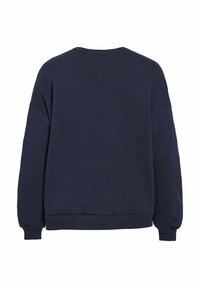 Svetlosiva majica s kozom s rebrastim okruglim izrezom, spuštenim ramenskim šavovima i rebrastim manžetama i donjim rubom. Glatka tekstura, ležeran kroj.