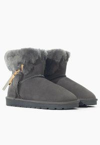Stivaletti alla caviglia in suede grigio con morbido rivestimento in pelliccia grigia, suola in gomma e etichetta decorativa in pelle marrone sul lato. Texture liscia, adatti per uso interno/esterno.