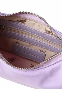 Interiorul unui rucsac din satin lavandă, cu un buzunar cu fermoar și o căptușeală netedă ce prezintă un model subtil cu logo. Accente de fermoar și hardware de culoare argintie.