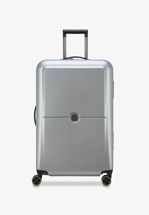 Maleta rígida plateada con forma rectangular, superficie texturizada, dos ruedas negras, un asa telescópica y un mecanismo de cierre central.