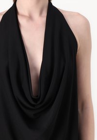 Mustat halterneck-topit, pehmeää kangasta, syvä kukka-aukko, rento mitoitus, sileä pinta, ilman näkyviä kuvioita tai metalliosia, minimalistinen muotoilu.