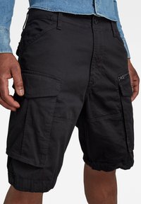 Svarta cargo-shorts gjorda av hållbart tyg, med flera fickor, en avspänd passform och elastiska muddar vid fållen.