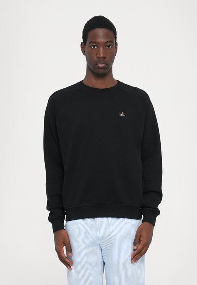 Schwarzes Sweatshirt mit geripptem Rundhalsausschnitt und langen Raglanärmeln, ausgestattet mit einem kleinen, bunten gestickten Logo auf der Brust.