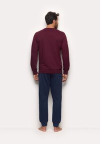 Maroon long-sleeve top with ribbed cuffs paired with navy joggers featuring elastic cuffs. Soft fabric, relaxed fit, no visible patterns.