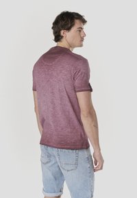 T-shirt dégradé bordeaux à manches courtes, tissu léger et revers de manches roulées. Associé à un short en denim bleu clair.