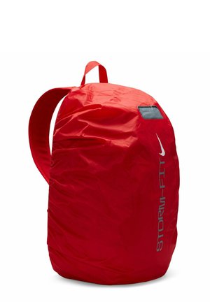 Red nylon backpack with a rounded shape, prominent storage compartment, and adjustable shoulder straps. Features a small window for identification.