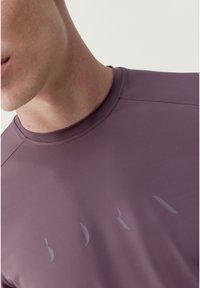 Kortærmet, slim-fit skjorte i dæmpet lilla stof med en glat tekstur. Har subtile logodetaljer i en lysere nuancer på forsiden.
