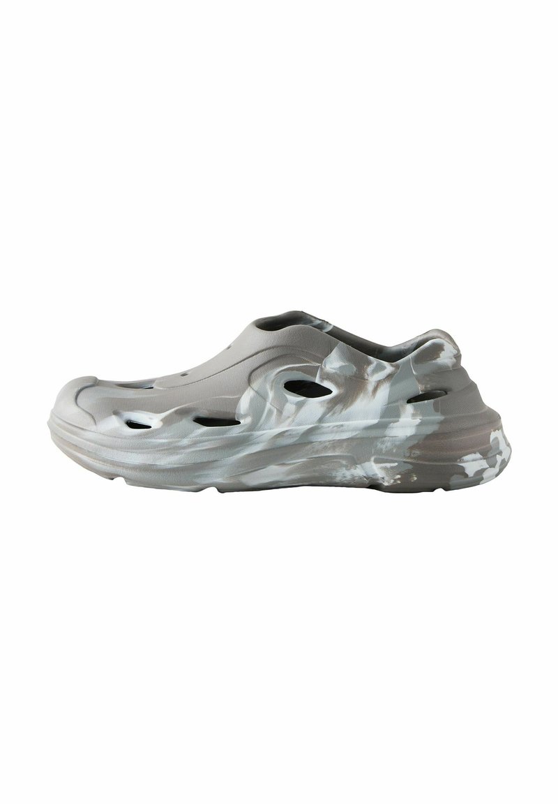Lys grå slip-on sko med bølgelignende abstrakte mønstre i hvid. Har udskårne ventilationshuller og en tykk, struktureret sål.