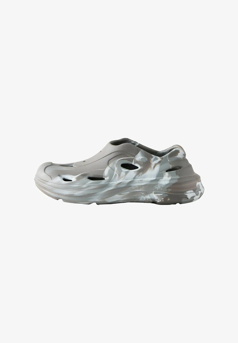 Light grey slip-on shoe with wave-like abstract patterns in white. Features cut-out ventilation holes and a thick, textured sole.