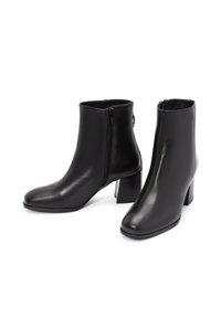 Botas de tobillo de cuero negro con un acabado suave y un panel lateral texturizado, con puntera redonda y un tacón cuadrado. Cierre de cremallera en el lado exterior.