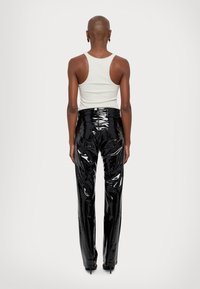 Zwarte, high-waisted broek gemaakt van glanzend, vinylachtig materiaal; heeft een getailleerde silhoutte met een gladde textuur en minimale details.