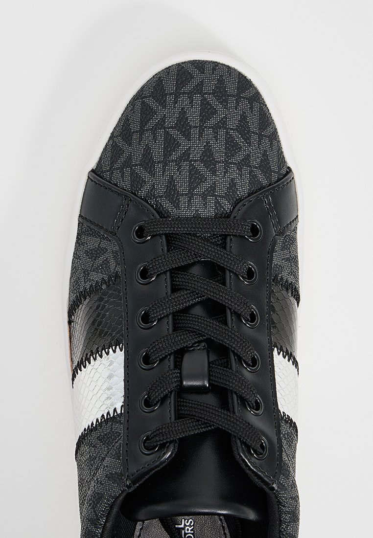 Zapatilla negra con parte superior de tejido estampado, que presenta acentos de cuero en negro, blanco y negro texturizado. Diseño con cordones y cordones redondos.