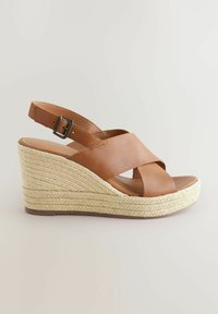 Brown leather wedge sandal with crossed straps, braided espadrille sole, and adjustable ankle strap. Features a curved wedge design.