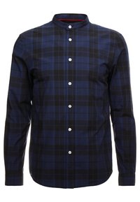 Camicia a quadri blu navy e nera con maniche lunghe, chiusura frontale con bottoni e colletto alla mandarino. Presenta bottoni bianchi e un accento rosso all'interno del colletto.