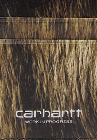 Carhartt denarnica z teksturiranim, rjavim vzorcem, ki spominja na leseno zrno, z belim logotipom, ki je prišito ob spodnjem robu.
