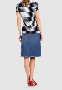 Pruhovaný krátký rukáv top v námořnické modři a bílé, spojený s sukní z denimu do délky kolen. Obsahuje třepené zakončení a červené vysoké podpatky.