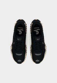 Μαύρα αθλητικά παπούτσια με επάνω μέρος από δίχτυ και συνθετικό υλικό, με χοντρή σόλα, εμφανή κορδόνια και αντίθετες μπεζ λεπτομέρειες.