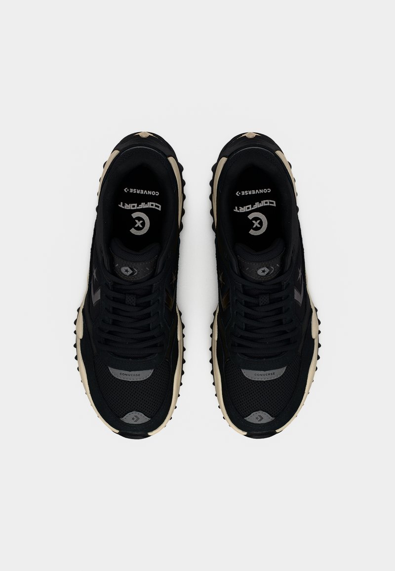 Zwarte sneakers met een bovenwerk van mesh en synthetisch materiaal, voorzien van een chunky zool, opvallende veters en contrasterende beige accenten.