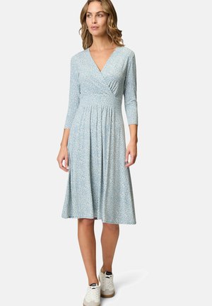 Light blue dress with a floral pattern, V-neck, three-quarter sleeves, and a flared skirt. Paired with white sneakers.