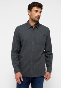 Grau gestreiftes Hemd mit Button-Down-Kragen, Fronttasche und dunklen Knöpfen, getragen mit blauer Jeans. Glatte Textur mit taillierter Passform.
