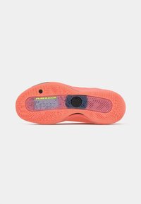 Skinnende orange sneakersål med mønstrede greb, synlig "AIR ZOOM" label og cirkulært sort logo i svangområdet.