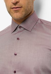 Maroon patterned shirt with a structured collar, featuring two matching buttons at the top, and a textured fabric with a subtle herringbone design.