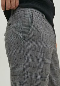 Grijze geruite broek met een gestructureerde afwerking, voorzien van een klassiek ruitenpatroon in zwart en wit, zijzakken en een getailleerde pasvorm.