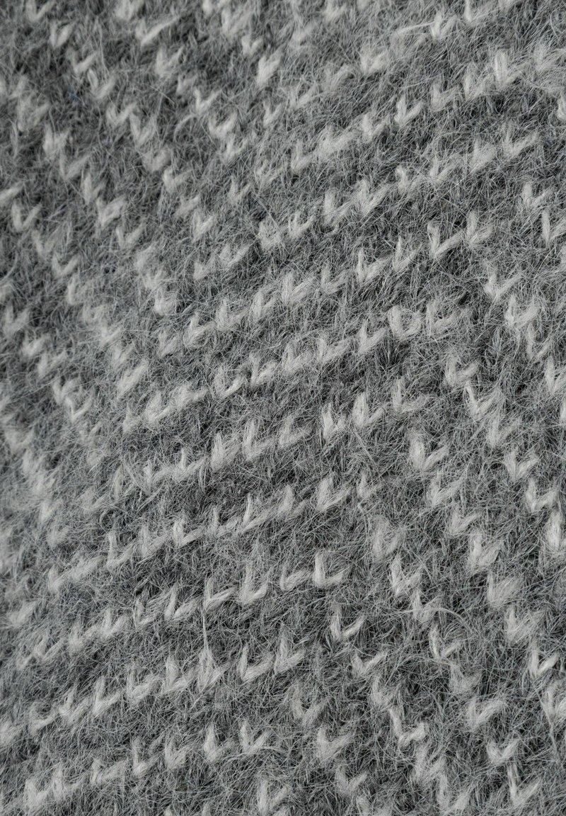 Textil con un patrón de espiga en gris y blanco, con una textura suave y peluda y un aspecto tejido.