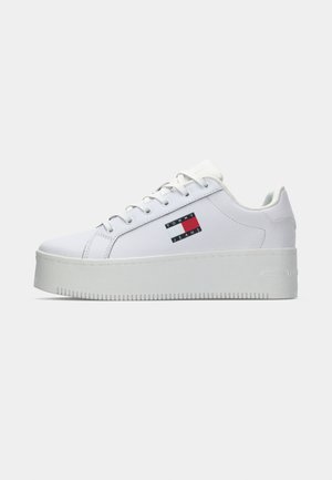 Sneaker platform bianche con upper in pelle liscia, dotate di una patch logo nera, rossa e blu sul lato e suola in gomma testurizzata.