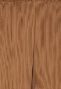 Jupe plissée marron avec une texture verticale, un tissu doux et un léger éclat. La ceinture est élastiquée pour plus de confort.