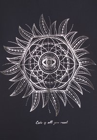 Fondo negro con un detallado mandala geométrico plateado con un ojo en el centro. El texto a continuación dice: "El amor es todo lo que necesitas."