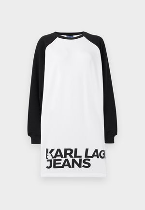 White and black oversized dress with raglan sleeves, featuring bold black text "KARL LAGERFELD JEANS" across the bottom. Smooth cotton material.