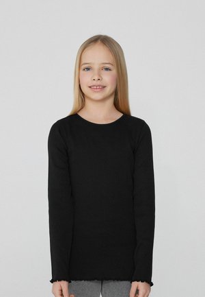 Langärmliges, schwarzes, geripptes Oberteil mit runder Ausschnitt und gewelltem Saum, getragen mit grauen Leggings. Glatte Textur, lässige Passform, minimale Details.