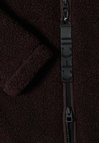 Dark brown textured fleece jacket with a black zipper and fabric pull tab labeled "Cecil" along the zipper line.