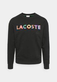 Czarna bluza z okrągłym dekoltem, z wielokolorowym, haftowanym napisem "LACOSTE" i małym logo z przodu. Miękka w dotyku.