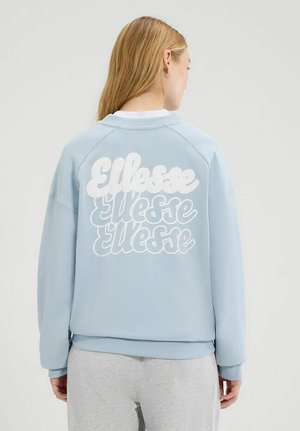 Sudadera azul claro con cuello redondo y mangas raglán. Cuenta con un gran logo estilizado en blanco en la parte posterior, textura suave y corte relajado.