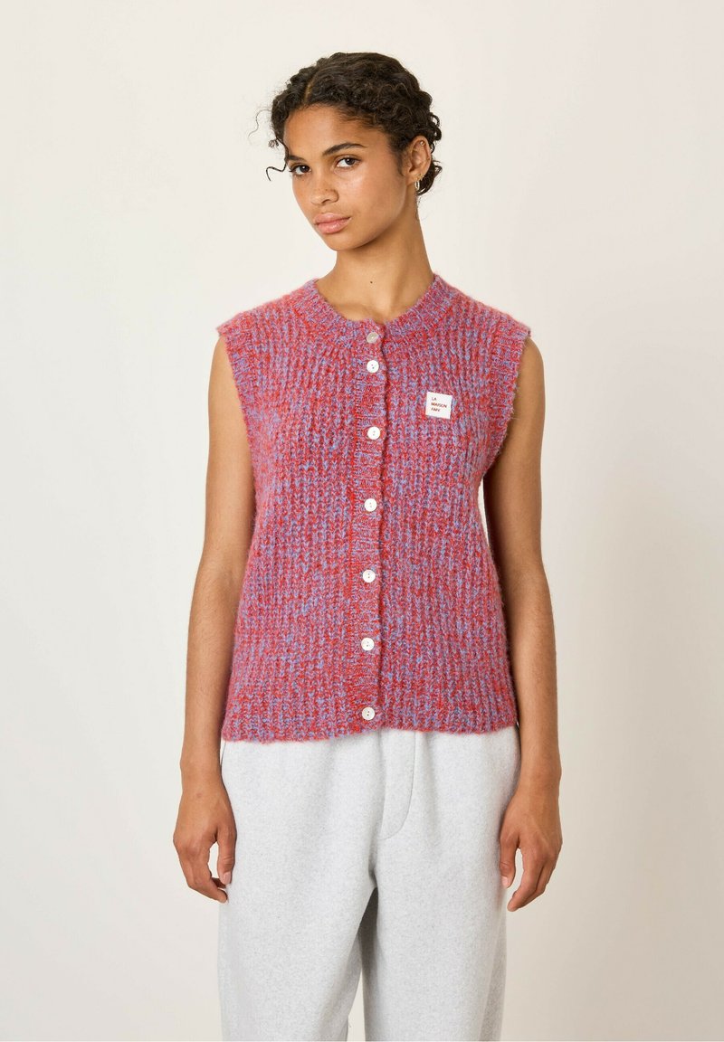 Bezruký pletený sveter v červených a modrých odtieňoch, s textúrovaným vzorom, okrúhlym výstrihom a piatimi bielymi gombíkmi pozdĺž prednej strany.