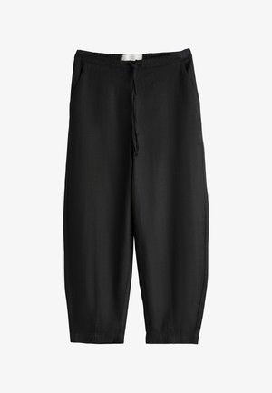 Black, loose-fitting linen pants with a drawstring waist, side pockets, tapered legs, and a smooth, textured finish.