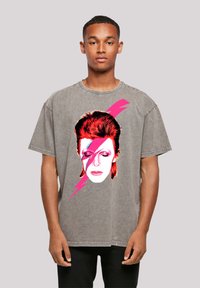 Gray oversized t-shirt featuring a printed graphic of a face with red hair and blue and pink lightning bolts on the front.