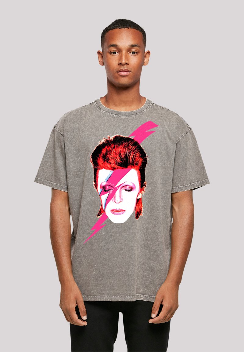 Gray oversized t-shirt featuring a printed graphic of a face with red hair and blue and pink lightning bolts on the front.