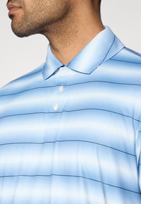 Ανοιχτό μπλε πόλο πουκάμισο με οριζόντιες ρίγες. Διαθέτει γιακά και τρία κουμπιά, κατασκευασμένο από απαλό, ελαφρύ ύφασμα.