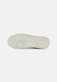 Podeszwa białego sneakersa Champion z widocznymi okrągłymi i liniowymi wzorami bieżnika oraz logo Champion wytłoczonym w okolicy pięty.