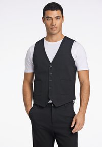 Schwarze Weste mit sechs Knöpfen, zwei vorderen Taschen und einem Reverskragen, getragen über einem weißen T-Shirt, mit taillierter Passform.