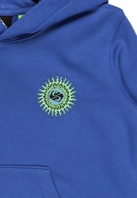 Sudadera azul hecha de tela suave, con un gráfico de sol verde que tiene un núcleo circular y rayos en forma de púa en el área del pecho izquierdo.