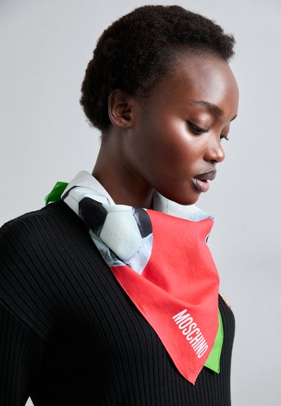 Multicolored silk scarf featuring a red base with a black and white soccer ball design, accented with green edges and "MOSCHINO" branding.