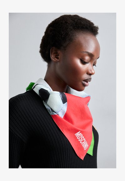 Multicolored silk scarf featuring a red base with a black and white soccer ball design, accented with green edges and "MOSCHINO" branding.