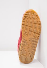 Röda mockasinsneakers med gummisulor. Sula har ett texturerat mönster och Nike-logotypen är präglad nära hälen.