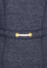 Tissu bleu marine moucheté avec une corde blanche traversant deux œillets ronds jaunes.