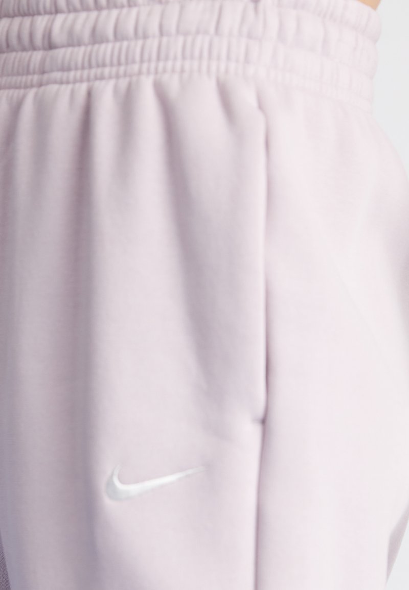 Hellrosa Jogginghosen aus weichem Material, mit einem elastischen Bund und einem kleinen, reflektierenden silbernen Nike-Logo an der Seite.